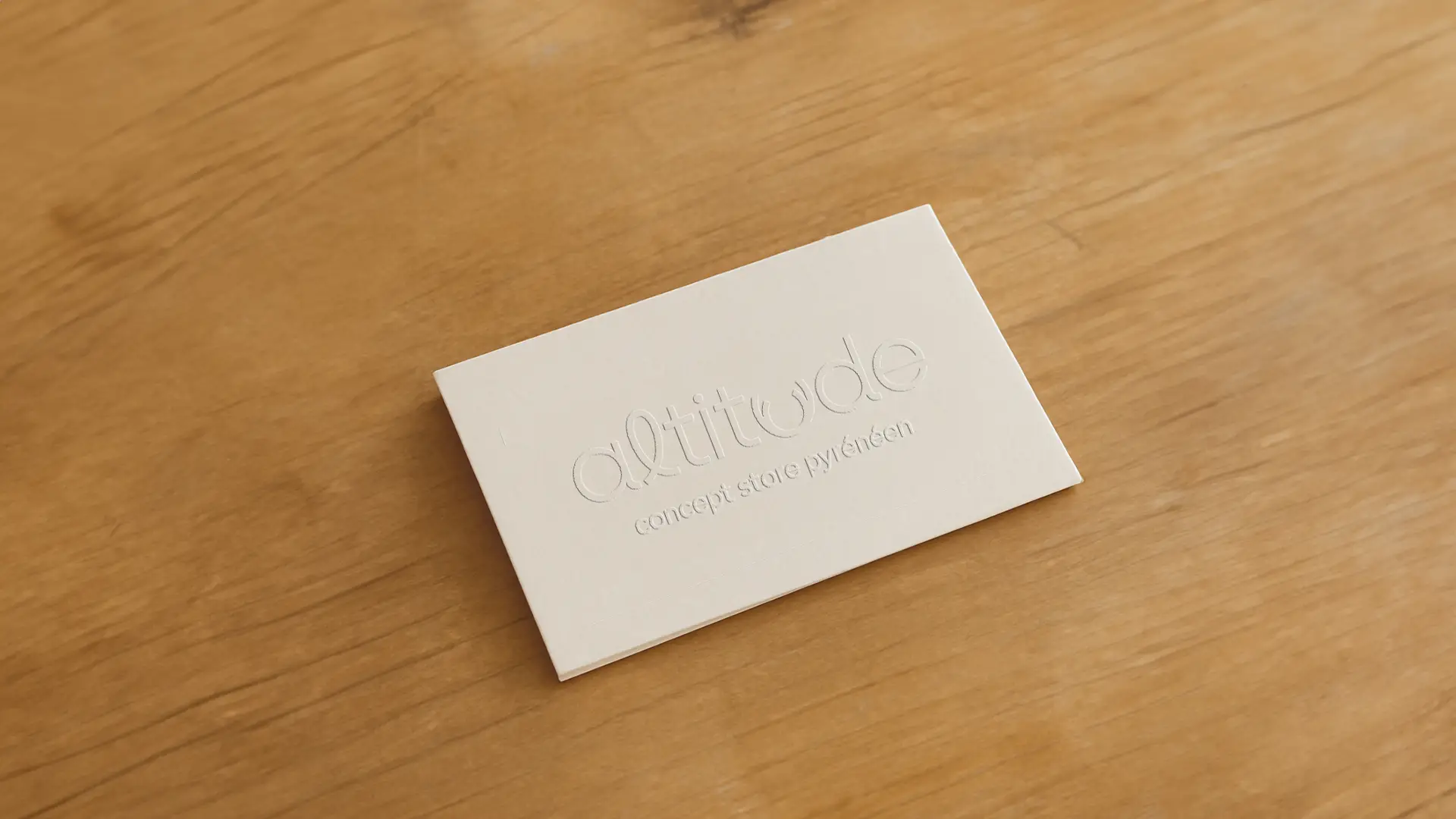 Maquette de carte de visite pour le concept store Altitude, avec un design minimaliste et embossé, portant le logo et le texte 'concept store Pyreneen'.